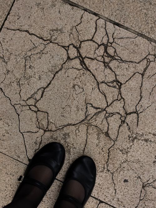 Free Black shoes on cracked pavement depicting urban decay and texture. Stock Photo