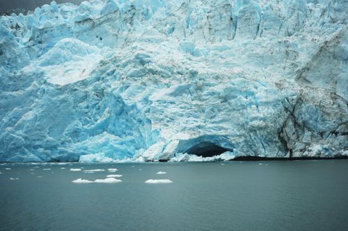 Free A serene view of a large ice glacier with pristine blue hues and floating icebergs in tranquil water. Stock Photo