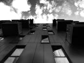 一张低角度拍摄的黑白照片，展现了一座现代建筑和戏剧性的云层