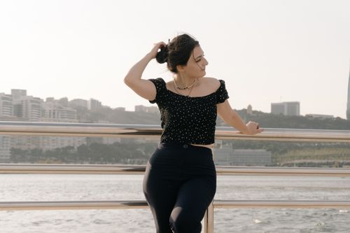 Free A young woman stands by the Baku waterfront, enjoying a sunny day with urban skyline in the background. Stock Photo