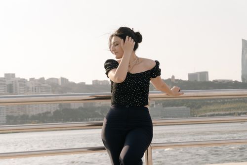 Free A stylish woman poses gracefully by the waterfront in Baku, Azerbaijan, with city skyline in the background. Stock Photo