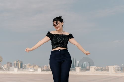 Free A woman dances joyfully on a sunny day with Baku's skyline in the background. Stock Photo