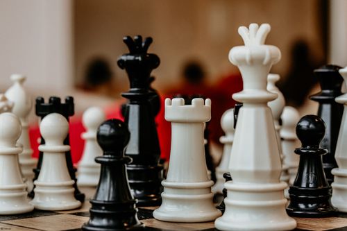 Free Detailed close-up of black and white chess pieces on a board in strategic arrangement indoors. Stock Photo