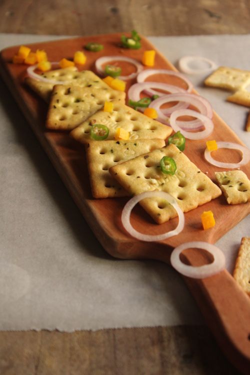 Free A rustic serving board with savory crackers, fresh onions, and peppers. Stock Photo