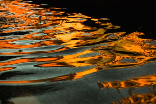 Free Stunning capture of warm orange reflections creating abstract patterns on rippling water. Stock Photo