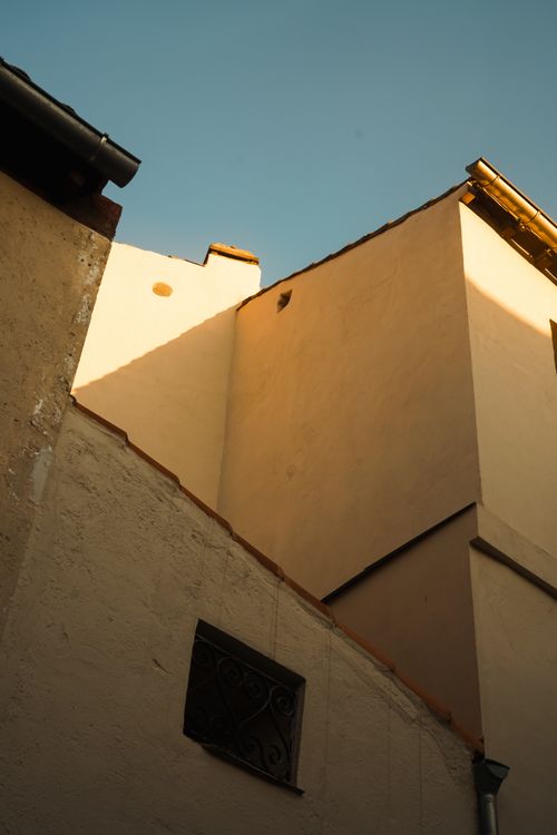 Free A sunlit view of European buildings with sharp angles and clear blue sky. Stock Photo
