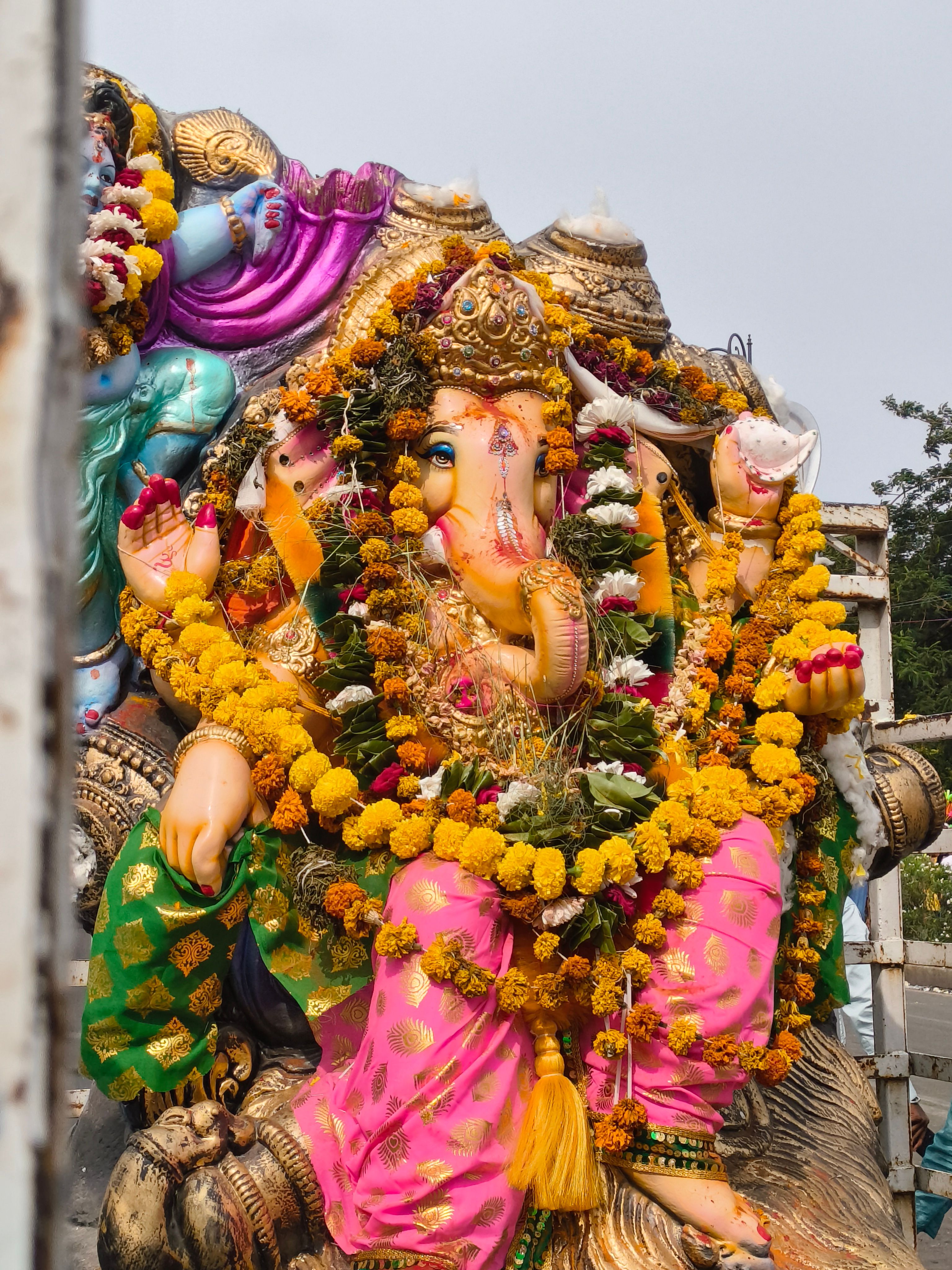 Vibrant statue of Lord Ganesh adorned with marigold garlands during a festival celebration.