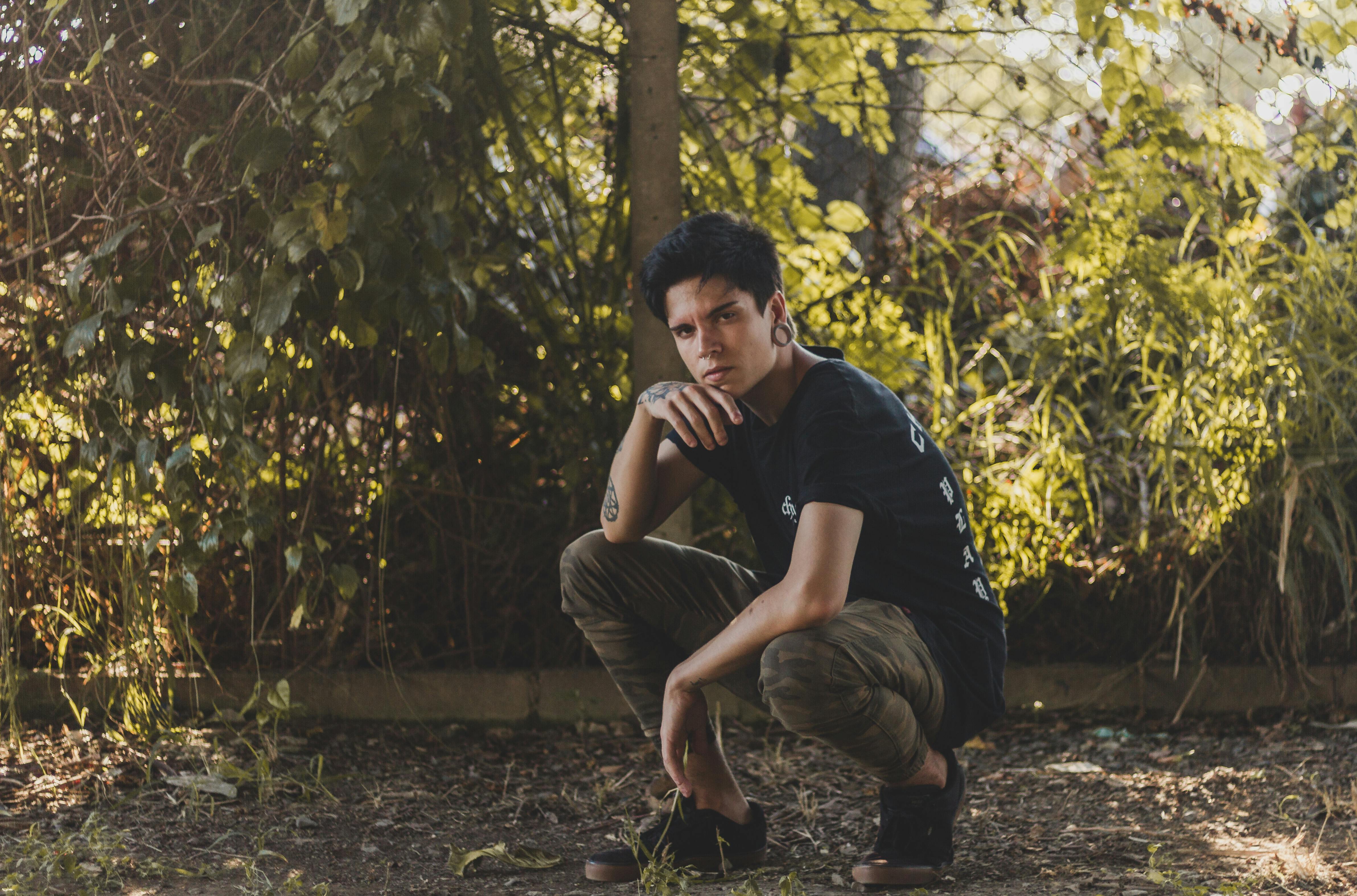 Man in Black T-shirt and Brown Pants Sitting on Ground · Free Stock Photo