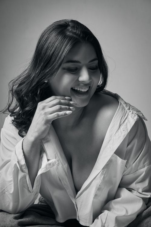 Free An artistic black and white portrait of a smiling woman in an open shirt, exuding elegance and warmth. Stock Photo
