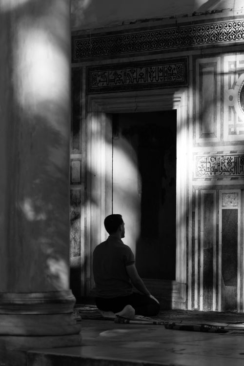 Free A person sits in meditation in a shadowed, historic courtyard, capturing serene reflection. Stock Photo