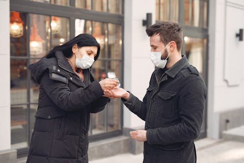 Woman Putting Hand Sanitizer on Man's Hand