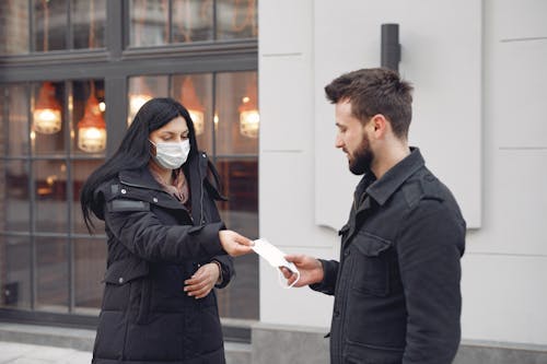 Young couple with medical masks on city street during cold season