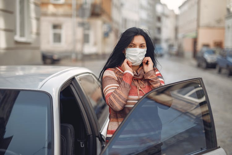 Young Woman Wearing Medical Mask Standing Near Automobile On Empty Urban Street