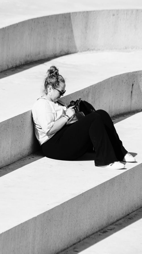 Free A woman sits relaxed on concrete steps, enjoying a sunny day in Durrës, Albania. Stock Photo