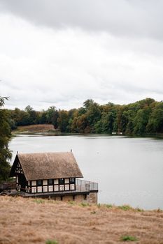 A picturesque lake house surrounded by lush greenery under a cloudy sky in England.