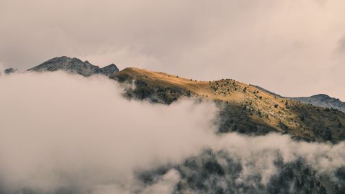 Free Mountain peak with scattered clouds and golden sunlight creating a dramatic landscape. Stock Photo