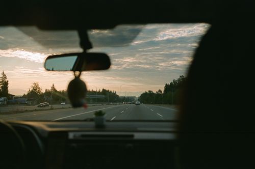 Free View of a highway and scenic landscape through a car windshield at sunset, capturing the essence of a peaceful road trip. Stock Photo