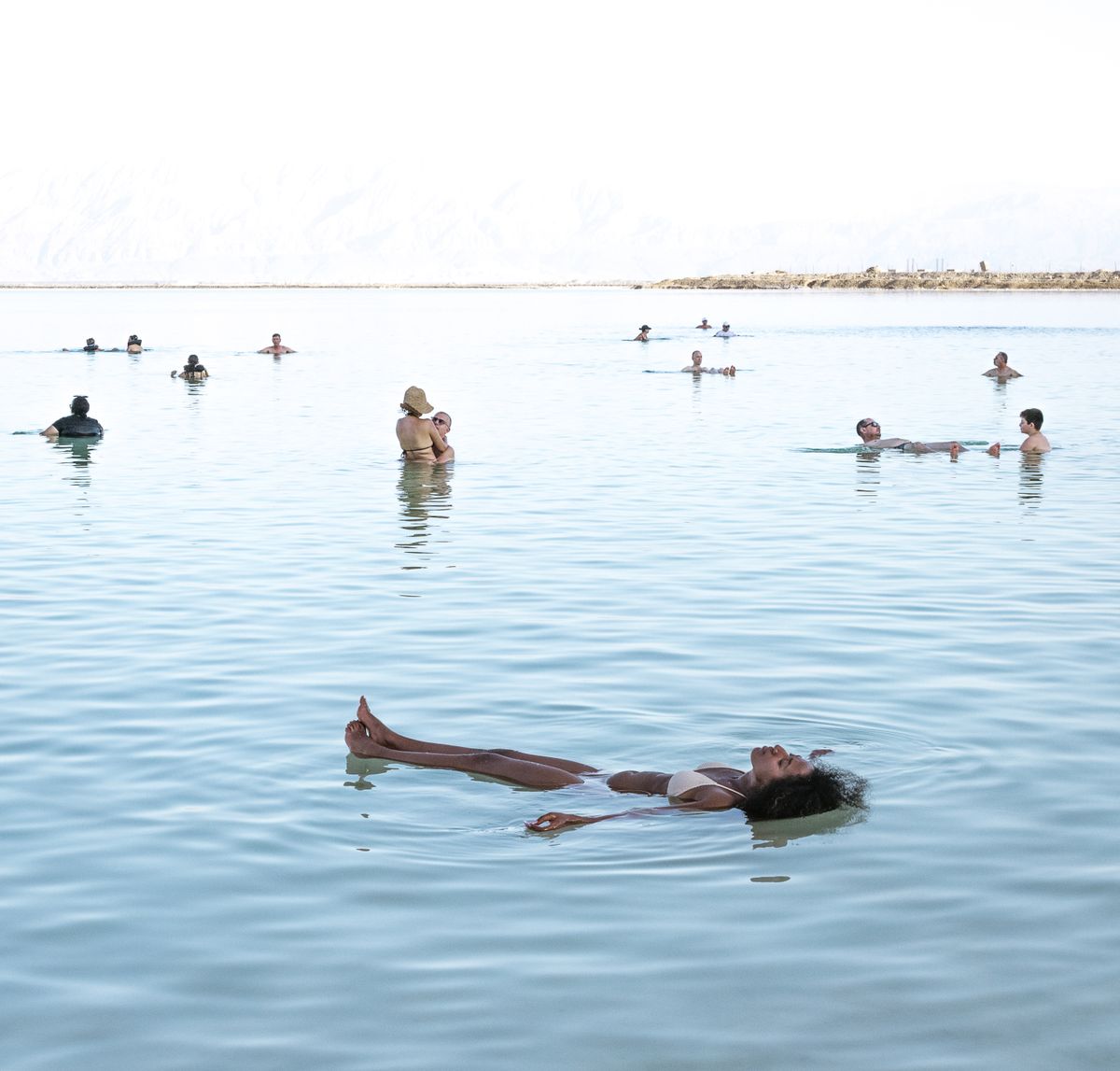 Swimmers floating on their backs in the calm water of the Dead Sea