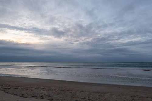 Free Tranquil sunrise over Atlantic Beach, North Carolina, serene ocean waves, and cloudy sky. Stock Photo