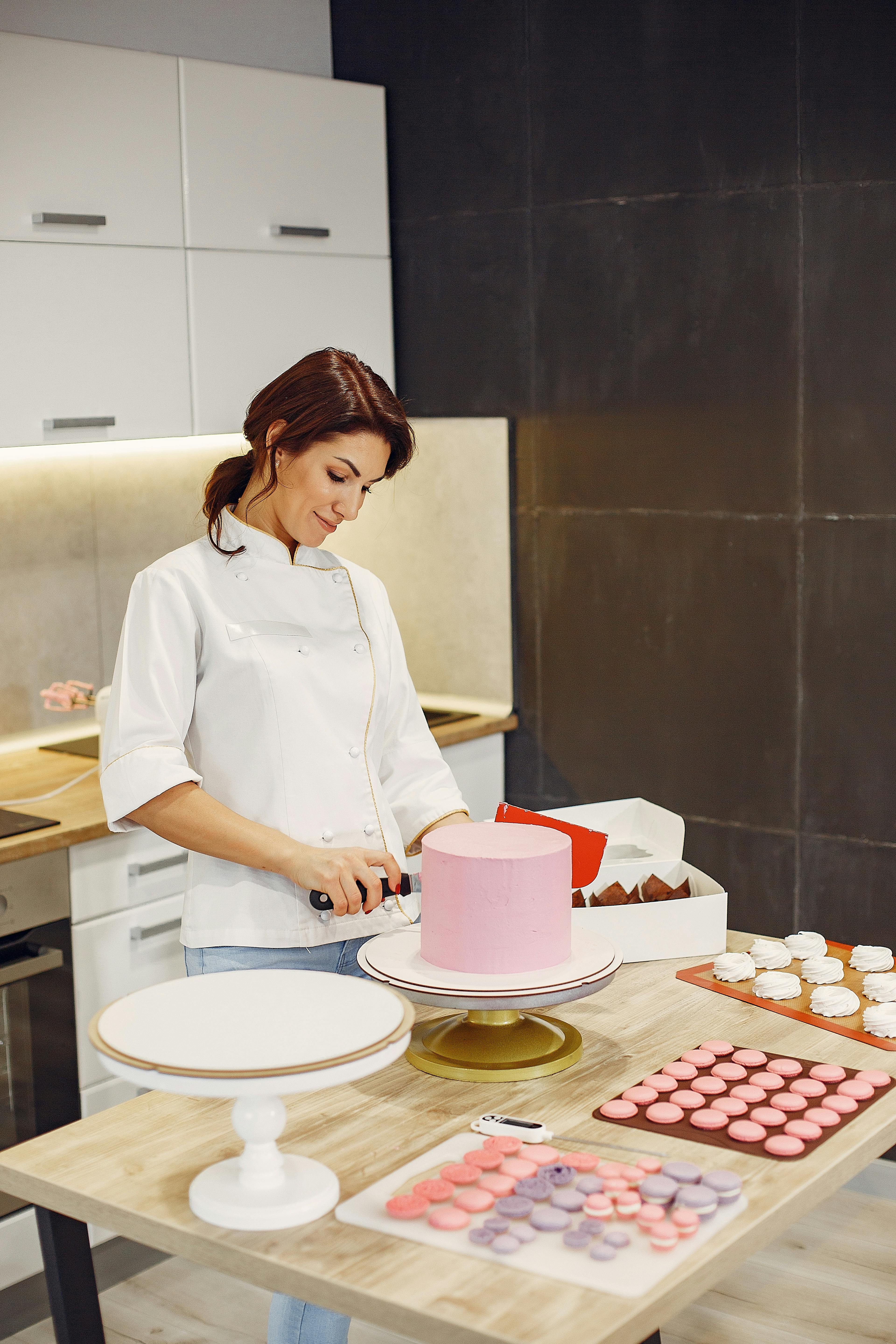 happy woman in process of cooking fresh cake and pastries in modern laboratory