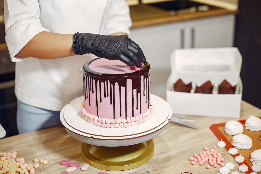 Pastry chef carefully decorating a celebration cake with small sweets