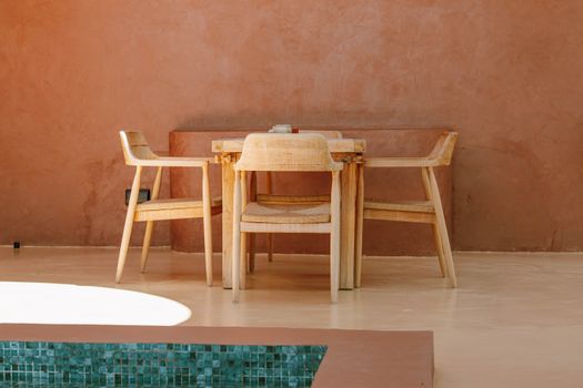 Simple wooden dining setup by a pool in Jambiani, Tanzania, exuding relaxation and modern style.