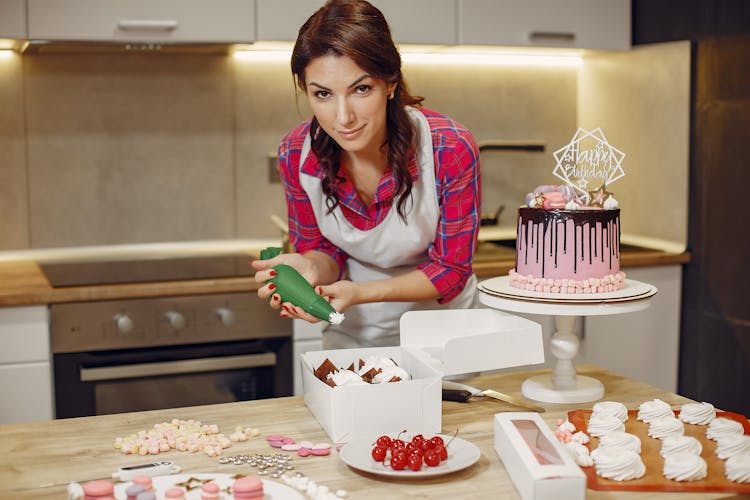 Woman In Red Checked Shirt Icing A Cake