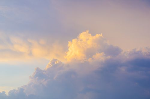 Free A stunning view of dramatic cumulus clouds illuminated by sunset hues in the sky. Stock Photo