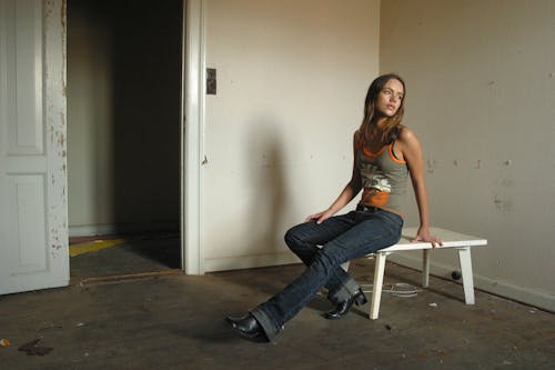 Slim dreamy woman sitting on table in old apartment