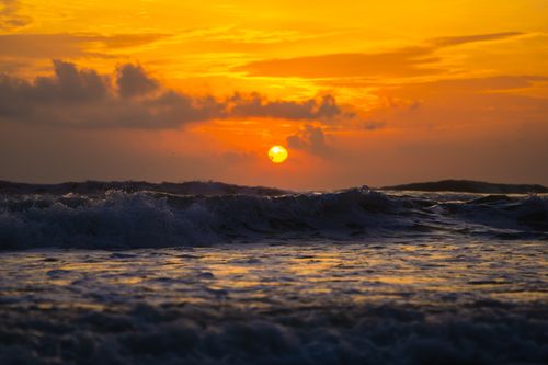 Free Sunset over ocean waves with vivid orange sky and dark clouds. Stock Photo