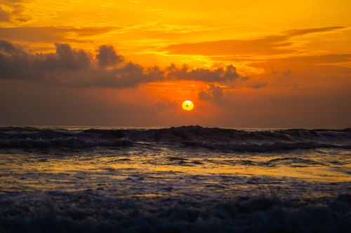Free Capture of a vibrant ocean sunset with golden hues and dramatic clouds, evoking tranquility and beauty. Stock Photo