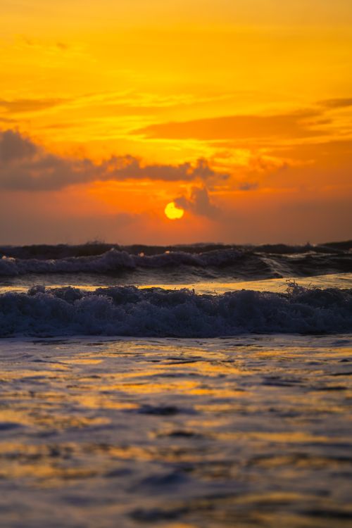 Free Captivating ocean sunset with vibrant orange hues and crashing waves. Stock Photo