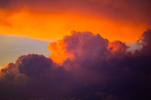 Free Vivid sunset clouds with a dramatic orange and purple palette, creating a stunning sky view. Stock Photo