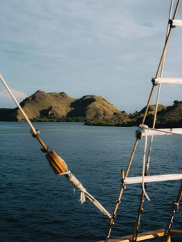 Beautiful landscape of Itäinen Nusa Tenggara, Indonesia, captured from a sailing boat with lush green hills and tranquil waters.