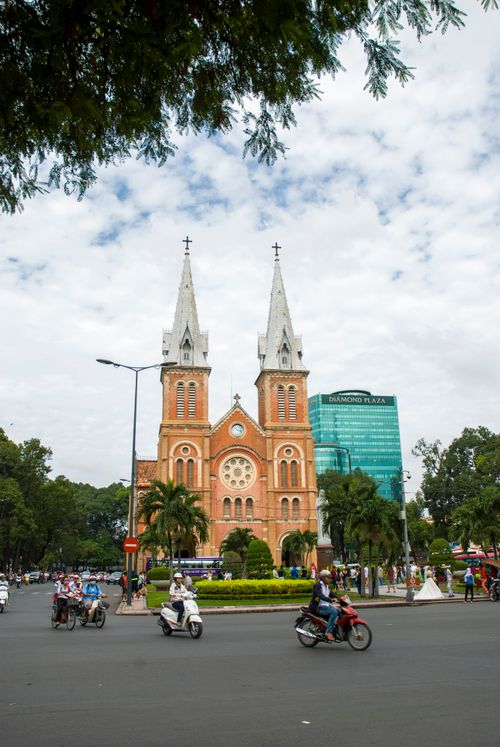 Free Basilica of Our Lady of The Immaculate Conception in bustling Ho Chi Minh City with motorcyclists in foreground. Stock Photo