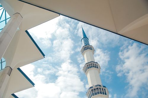 Free A majestic minaret soaring into the sky with modern architectural elements framing the view. Stock Photo