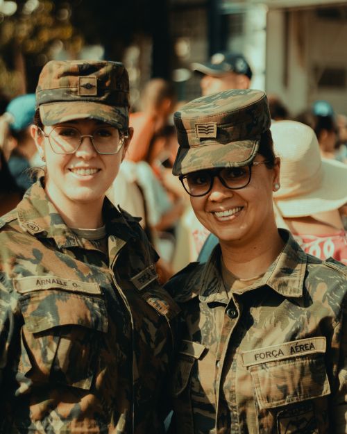 Free Two women in military camouflage smiling at an outdoor event, showcasing camaraderie. Stock Photo