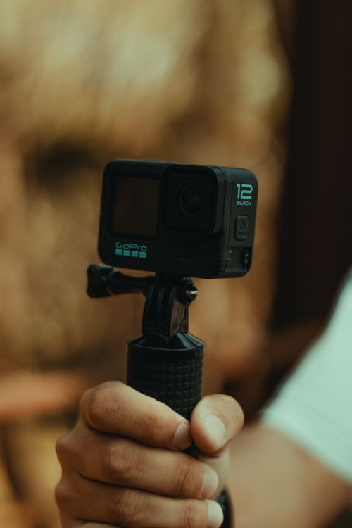 Free A person holds a compact action camera mounted on a grip, perfect for adventure. Stock Photo