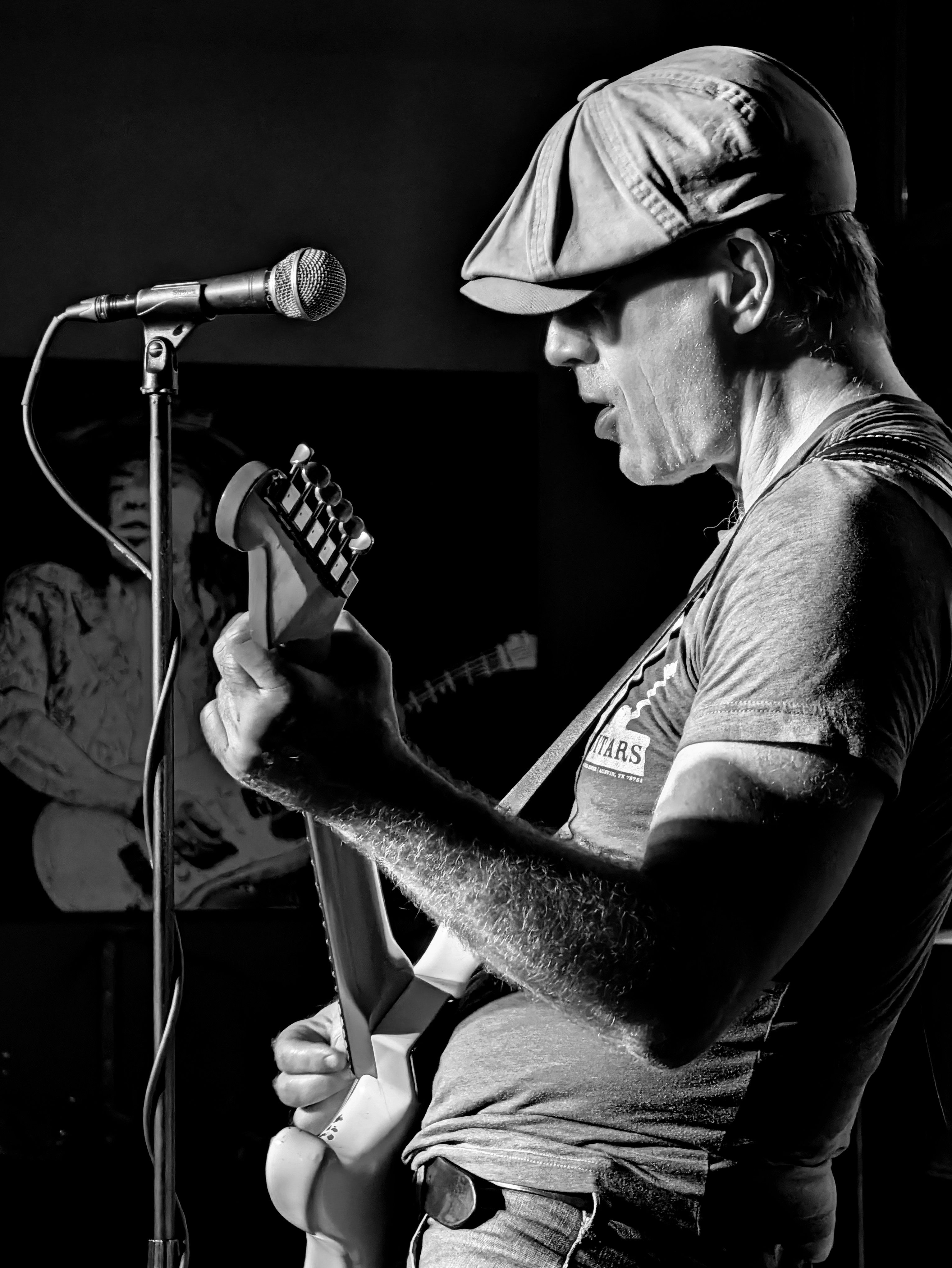 A captivating black and white portrait of a guitarist in action during a live performance, capturing raw musical energy.