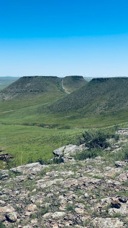 Free A breathtaking view of twin hills surrounded by lush green landscape under a clear blue sky. Stock Photo