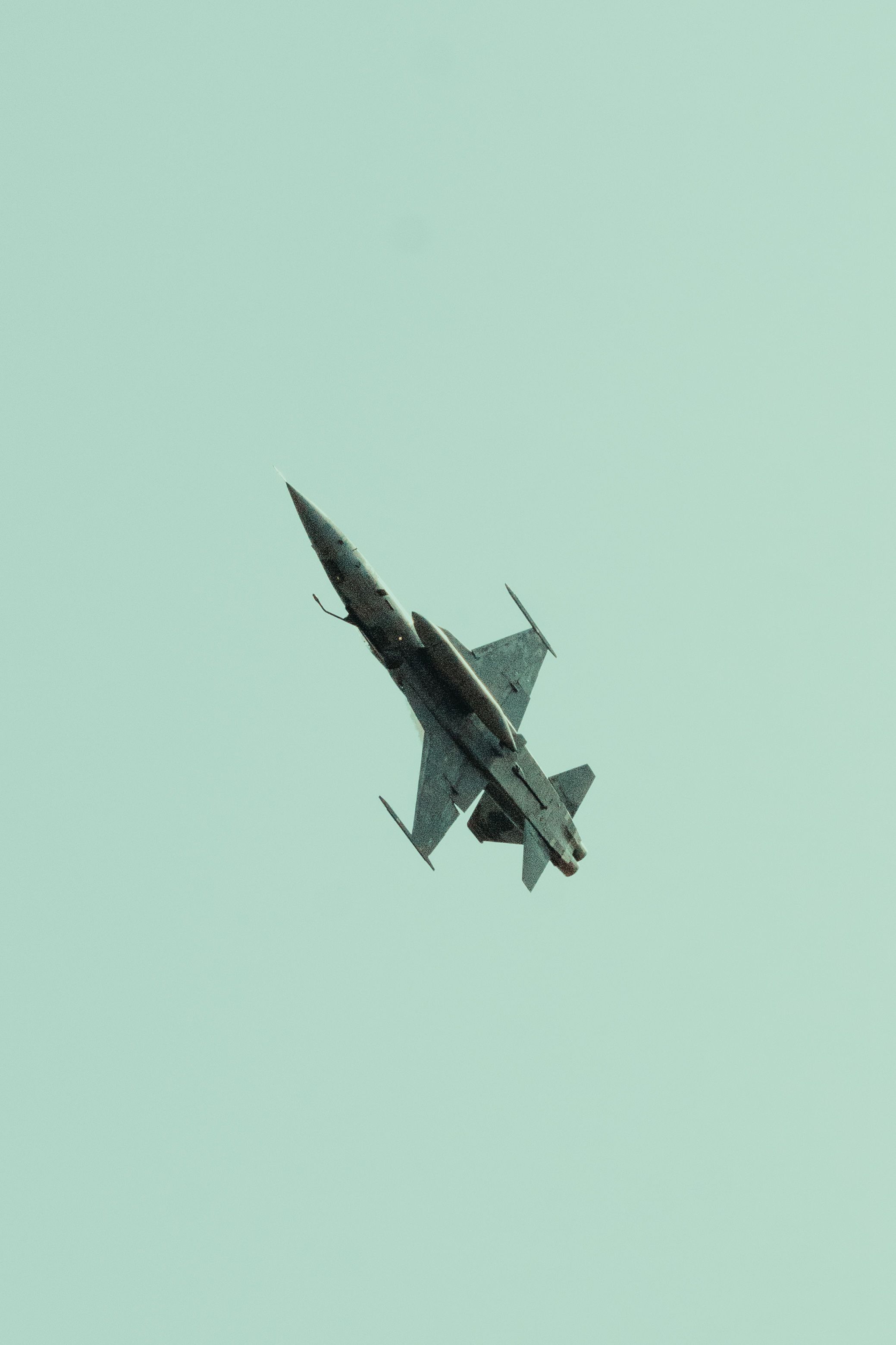 A military jet performing an aerial maneuver against a clear sky, showcasing agility and speed.