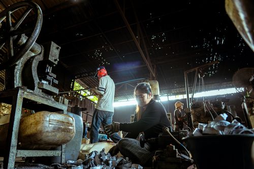 Free Multiple workers engaged in tasks within an industrial factory, highlighting machinery and labor. Stock Photo