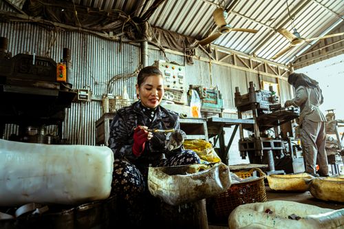 Free A woman engaged in manual labor in an industrial factory setting, surrounded by machinery and tools. Stock Photo