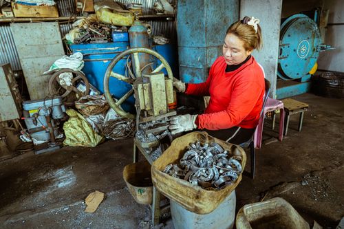 Free Female worker in red sweater operates machinery in a cluttered industrial setting. Stock Photo
