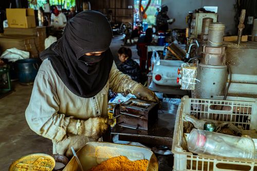 Free A worker wearing protective gear operates machinery in an indoor industrial setting. Stock Photo