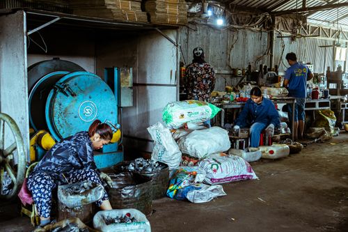 Free Workers sorting materials in a recycling plant, emphasizing manual labor in waste management. Stock Photo