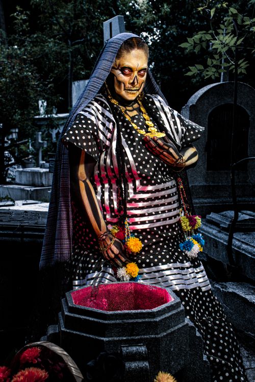 Free Colorful Day of the Dead Catrina statue in cemetery with vibrant marigolds Stock Photo