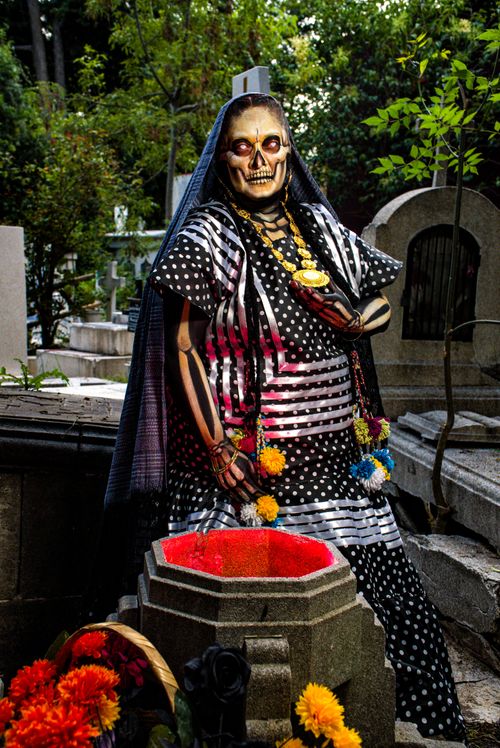 Free Vibrant Day of the Dead costume and face paint in a graveyard setting. Stock Photo