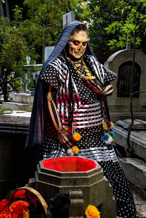 Free Colorful Day of the Dead skeleton figure in a cemetery, adorned with flowers. Stock Photo