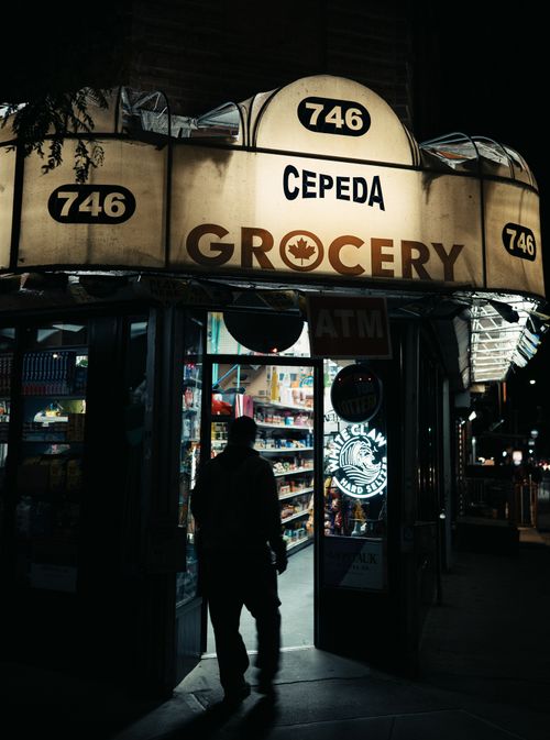 Free Silhouette of a person entering Cepeda Grocery under neon lights, New York City at night. Stock Photo